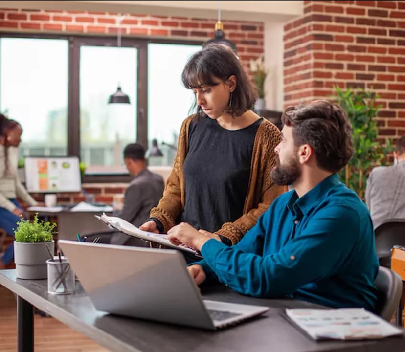 Two colleagues reviewing paperwork together at a desk