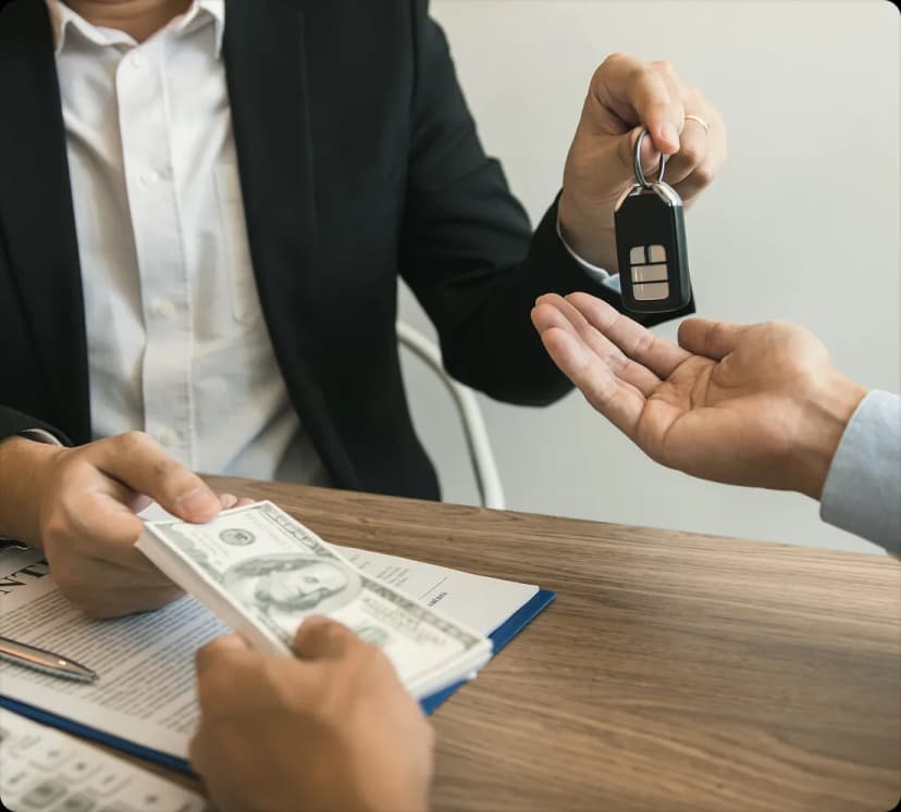 House keys handed across a desk while a stack of cash is passed over a contract